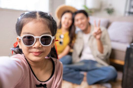 Child wearing sunglasses taking family selfie at home
