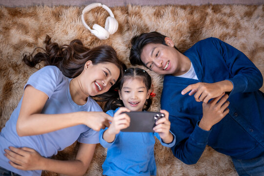 Asian family smiling, taking selfie with smartphone