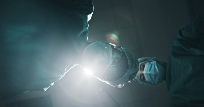 Below, people and surgeon in theatre at hospital for surgery, medical procedure and critical condition. Pov, team and doctor inspection for emergency operation, organ transplant and healthcare crisis