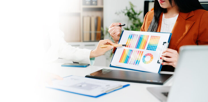 Creative female designers using pen tablet and color palette for UX UI design in modern office.