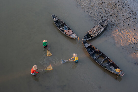 Top view of three unidentified men using fishing nets in shallow water