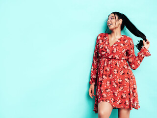Young beautiful smiling female in trendy summer red dress clothes. Sexy carefree woman posing near...