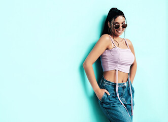 Young beautiful smiling female in trendy summer jeans and top clothes. Carefree woman posing near...