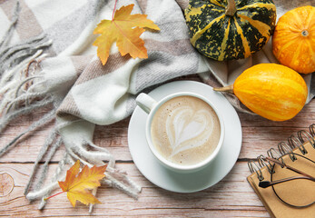 Autumn decoration with coffee cup, pumpkins, and a warm blanket
