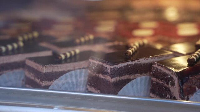 Delight in the close-up view of rich chocolate pastries with creamy layers, captured in soft lighting. This detailed shot highlights gourmet dessert presentation in a patisserie setting.