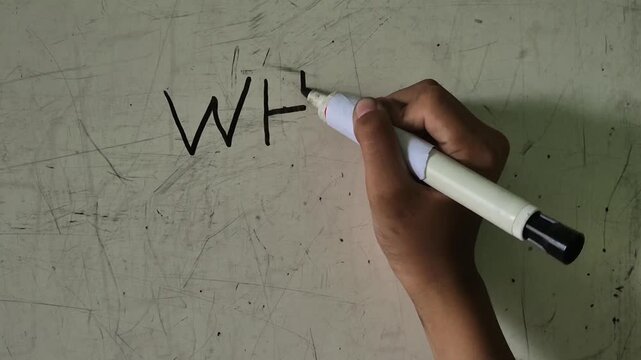 The male student's hand is writing WHY? on the board using marker pen