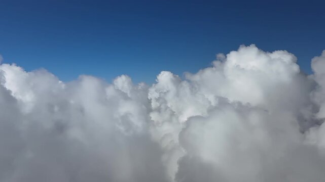 A pilot&rsquo;s perspective from a jet cokpit while flying art supersonic speed above an endless layer of cottony clouds, doing a left turn, under a deep blue sky.