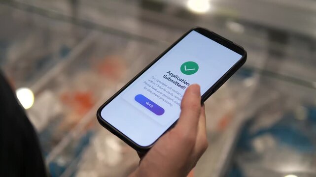 A shopper in a grocery store uses her smartphone to secure instant financial credit, clicking the approval button and receiving immediate confirmation. 