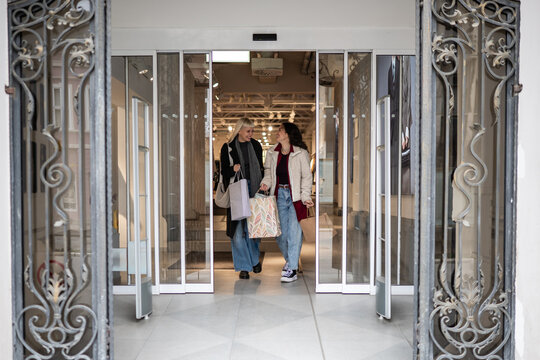 Happy young women leaving store after shopping