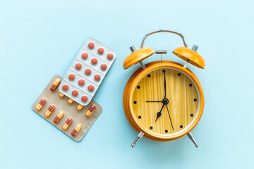 Medical treatment pills and vintage alarm clock, top view. Time to take medicine concept