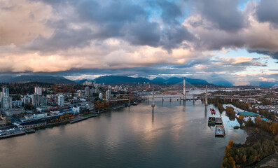 Obraz premium Aerial Cityscape Over The River With Bridges And Mountains In New Westminster, Greater Vancouver