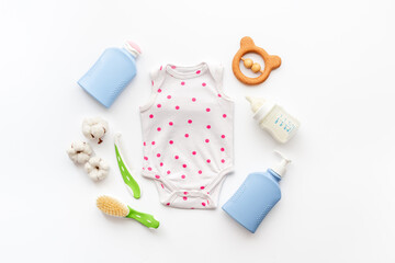 Set of baby hygiene cosmetic products - shampoo and soap with a comb. Eco friendly accessories - bodysuit and wooden toys with bottle of milk on white background, top view