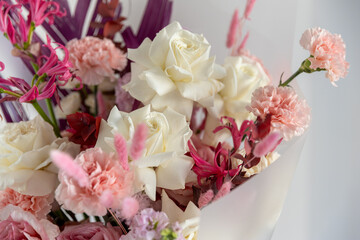 Macro close-up shot highlighting the texture of creamy white roses and delicate pink carnations in a vibrant, stylish modern flower arrangement