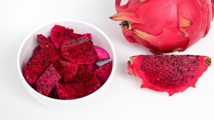 Close up of delicious, healthy of fresh red ripe Dragon Fruits (Pitaya) cut pieces, cubes in white bowl isolated on pink background