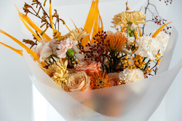 Extreme close-up of a richly textured autumn bouquet with peach roses, orange protea, yellow accent flowers, and striking red hypericum berries