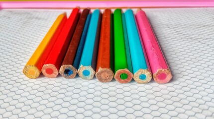 Close-up of a vibrant row of hexagonal colored pencils on a textured white surface, ready for creative drawing and coloring