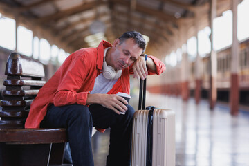 Tired man sleeping on bench at train station platform