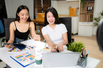 Female fashion designers discussing new clothing collection ideas in studio.