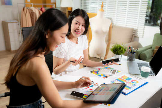 Female fashion designers discussing new clothing collection ideas in studio.