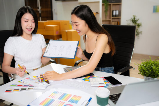 Female fashion designers discussing new clothing collection ideas in studio.