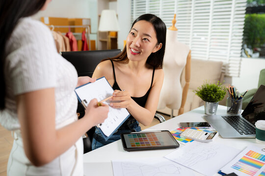 Female fashion designers discussing new clothing collection ideas in studio.