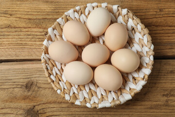 Chicken eggs in a basket placed on a wooden background