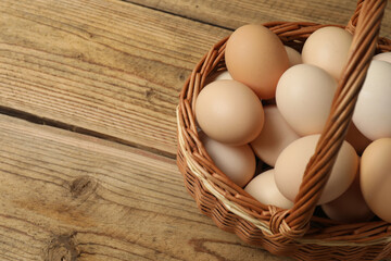 Chicken eggs in a basket placed on a wooden background