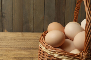 Chicken eggs in a basket placed on a wooden background