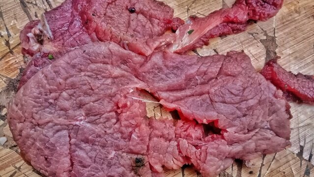 Close-up of marbled raw beef steak on a wooden cutting board, ready for cooking or grilling preparations