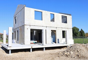 New residential building under  construction with raw concrete prefab walls and thermal insulation board partially installed.