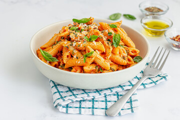 Penne pasta with tomato sauce, topped with fresh basil leaves