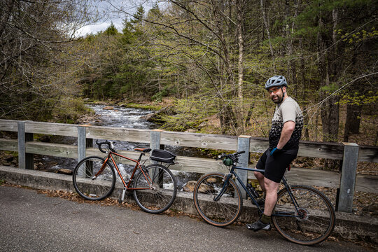 A man pauses near a stream while riding gravel bikes