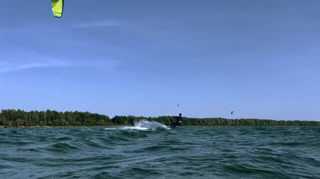 Kitesurfer Riding in the Lake with Blue Sky and Kites Background