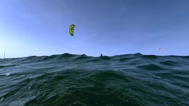 Kitesurfer Riding in the Ocean with Blue Sky and Kites Background