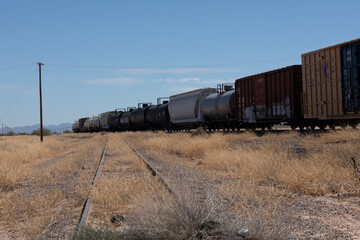 Obraz premium Passing train in dried grassy western rural environment