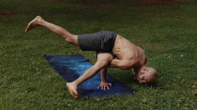 Yoga practice on grass with unique arm balance position
