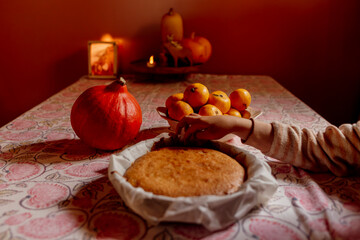 Hand cutting homemade cake beside pumpkin and fruit bowl
