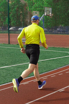 Man jogging with basketball court in background, rear view