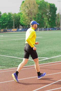 Man running on sunny day at stadium, back view