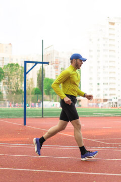 Runner training at city stadium with apartment buildings in back