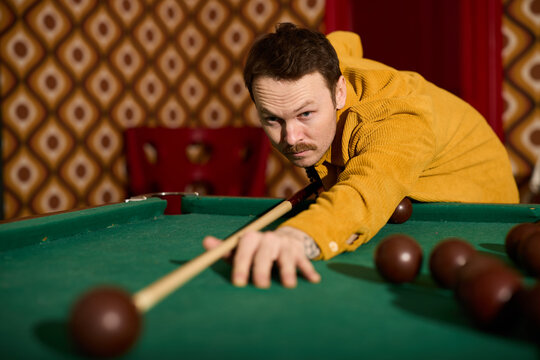 Man plays billiards in a vintage themed bar during the evening