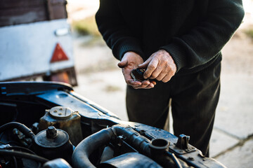 Senior man working on car engine while inspecting equipment