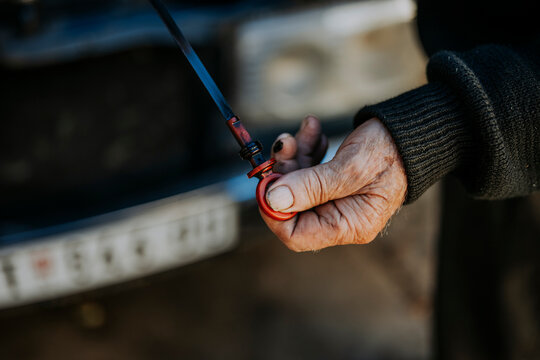 Man checking oil level in car engine at outdoor location