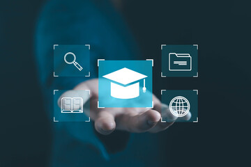 Businessman hand holding digital graduation cap icon surrounded by book, search, folder, and globe symbols, representing online education, e-learning, and digital knowledge concept.