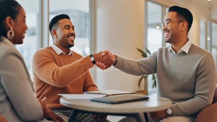 Two smiling businessmen shake hands across a table, with a colleague observing, signifying a successful agreement or partnership.