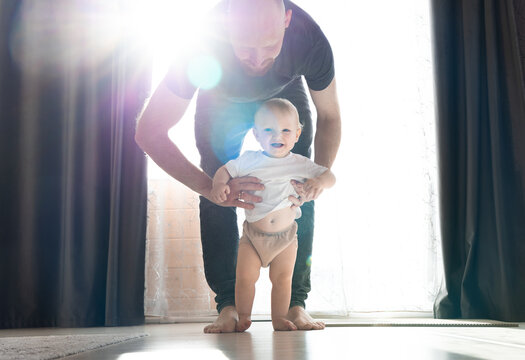 Dad supports his son as he learns to walk