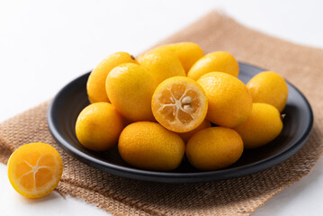 Fresh kumquats fruit on black plate