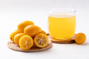 Fresh kumquats fruit and orange juice on white background