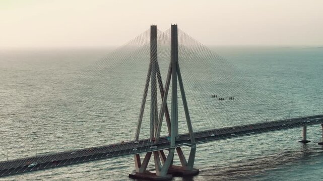 Cinematic aerial view of the Bandra Worli Sea Link in Mumbai, Maharashtra, India, during the monsoon season, with dramatic clouds and top shots of moving cars, captured from above the clouds.