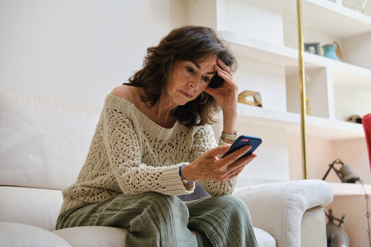 front view of Senior woman receiving bad news on smartphone feeling stressed - Powered by Adobe